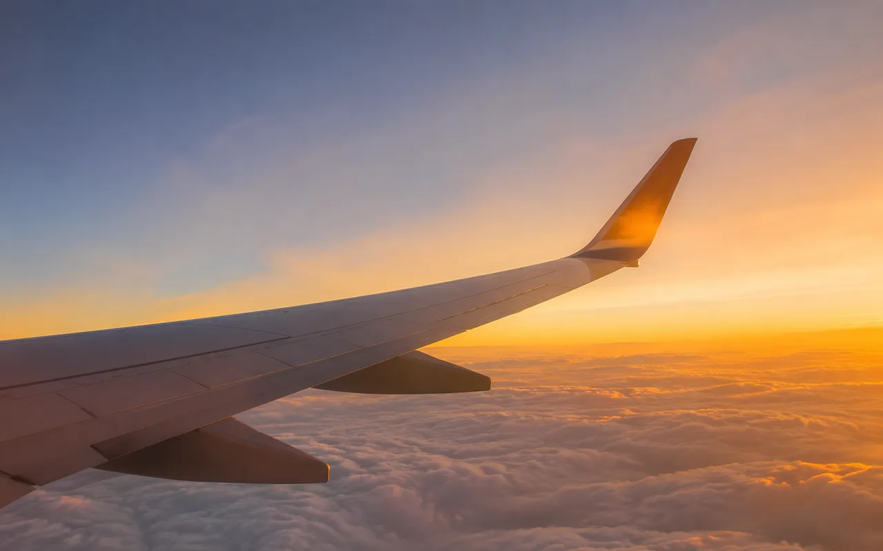 Aircraft wing above clouds at golden hour — cheapest time to book flights from the UK in 2026