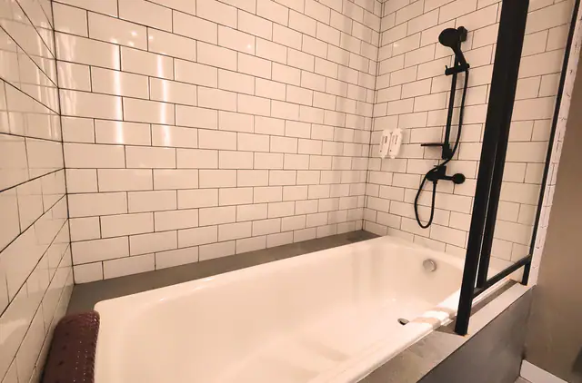 Bathtub and walk-in shower with white metro tiling at Citadines Connect Airport Jakarta