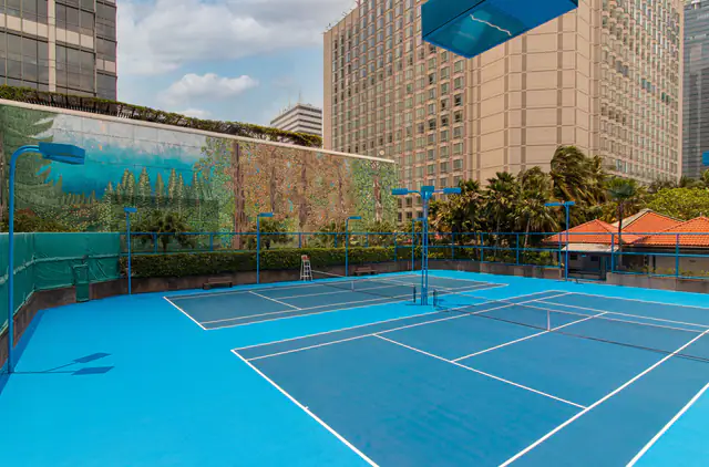 Rooftop tennis courts at Grand Hyatt Jakarta, surrounded by Thamrin towers
