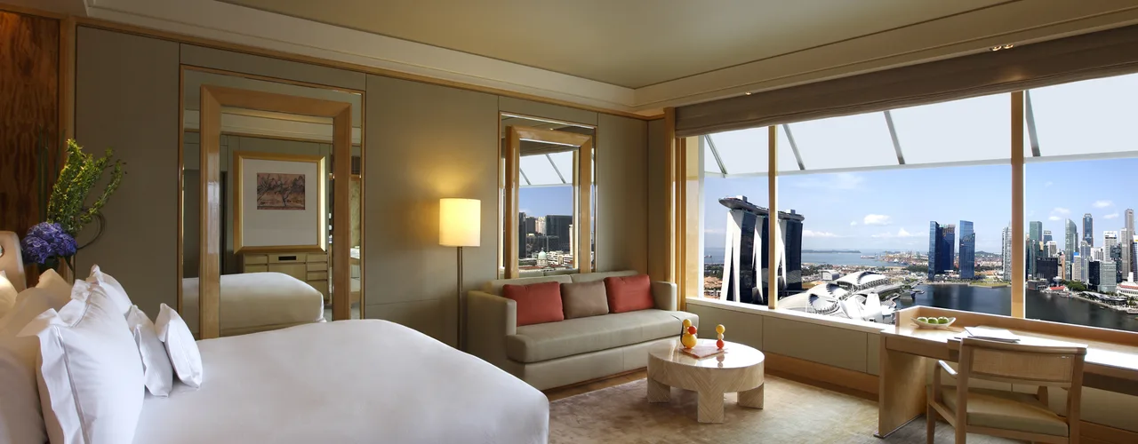 Luxury hotel suite with bed and living area overlooking Marina Bay and Marina Bay Sands in Singapore
