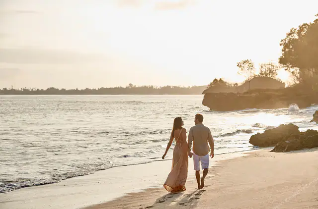 Couple walking the sand at the Raffles Bali beach cove