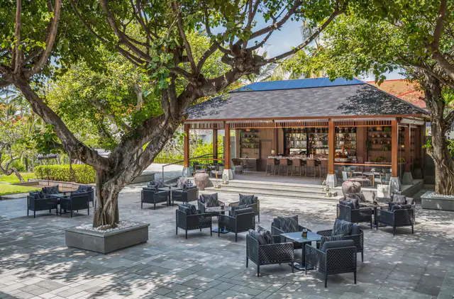 Shaded terrace lounge beneath a banyan tree at The Laguna Bali